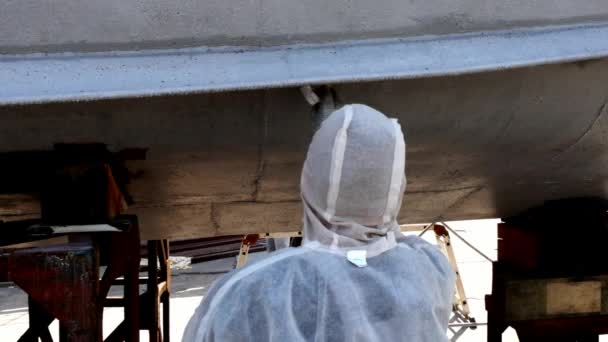 Worker paints metal of old rusty ship propeller at shipyard in port. — Stock Video