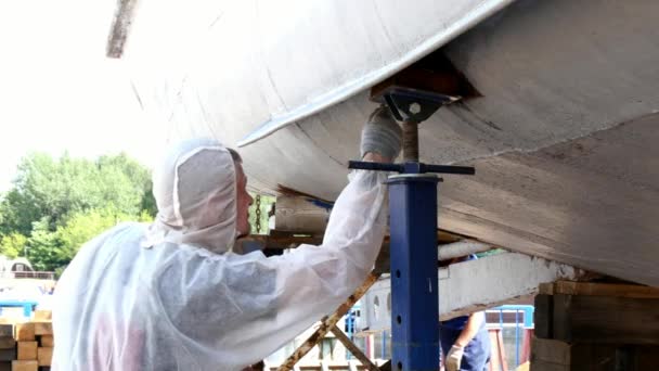 Trabajador pinta metal de vieja hélice de barco oxidado en astillero en puerto . — Vídeos de Stock