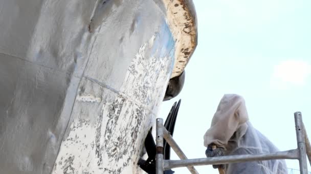 Un ouvrier peint le métal d'une vieille hélice rouillée au chantier naval du port . — Video