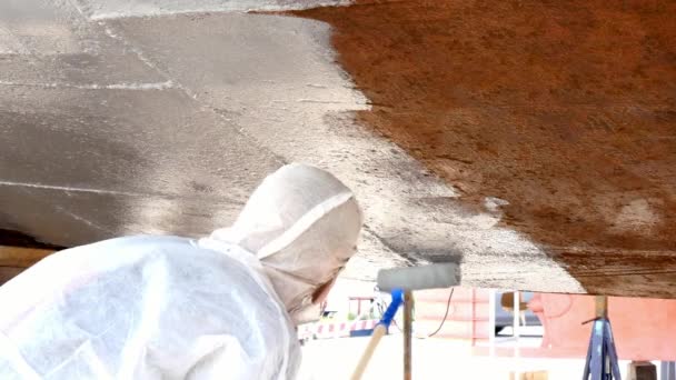 Worker paints metal of old rusty ship propeller at shipyard in port. — Stock Video