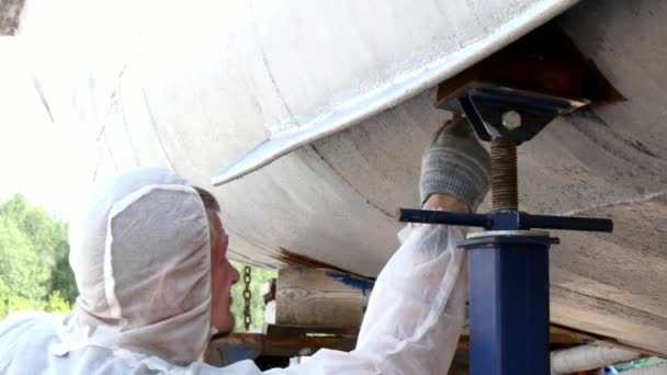 Un ouvrier peint le métal d'une vieille hélice rouillée au chantier naval du port . — Video