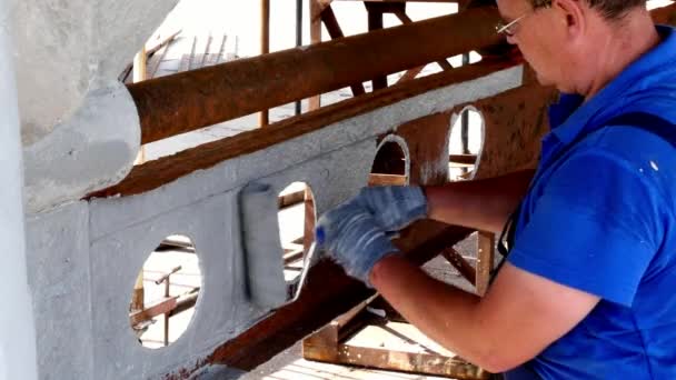 Un ouvrier peint le métal d'une vieille hélice rouillée au chantier naval du port . — Video