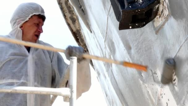 Un ouvrier peint le métal d'une vieille hélice rouillée au chantier naval du port . — Video