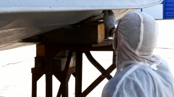 Un ouvrier peint le métal d'une vieille hélice rouillée au chantier naval du port . — Video