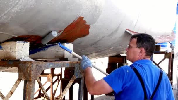 Trabalhador pinta metal de velho hélice de navio enferrujado no estaleiro no porto . — Vídeo de Stock