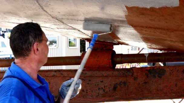 Worker paints metal of old rusty ship propeller at shipyard in port. — Stock Video