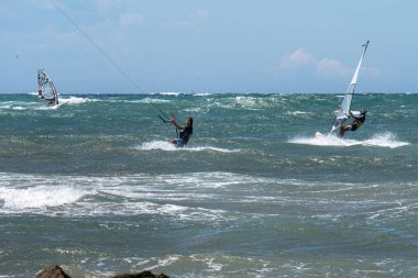 Rüzgarlı bir günde çok dalgalı bir denizle uçurtma sörfü ve rüzgar sörfü.