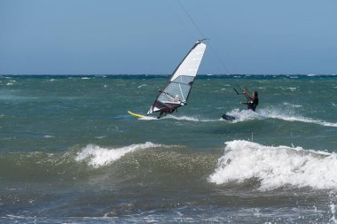 Rüzgarlı bir günde çok dalgalı bir denizle uçurtma sörfü ve rüzgar sörfü.