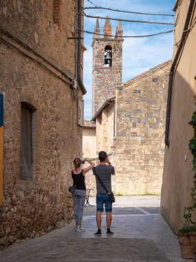 Monteriggioni-Siena, İtalya - Ağustos 2021: Bir Erkek ve Bir Kız, Monteriggioni, Siena 'daki Piazza Roma' daki Santa Maria Assunta Kilisesi 'nin önündeki Narrow Caddesi' nden Resim Çekiyor - İtalya.