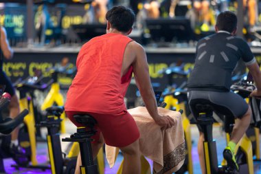 Spor salonunda egzersiz yapan insanlar, spor bisikletleriyle spor yapıyorlar..