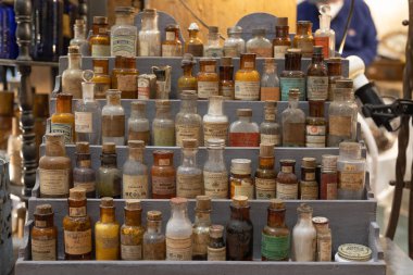 Tahta bir vitrinde kimyasal bileşikler içeren antika cam şişeler..