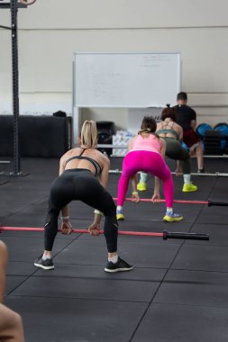 Spor salonunda beden eğitimi: Sınıfta halterle egzersiz yapan kızlar.