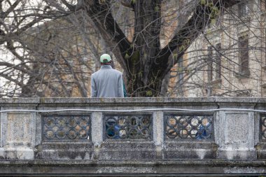 Parma şehrinin merkezindeki köprüde dikilen erkekler birbirleriyle konuşuyorlar, İtalya.