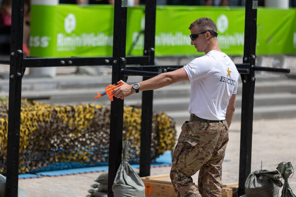 Soldier in Uniform and Camouflage Pants Playfully firing an Orange Water Gun.