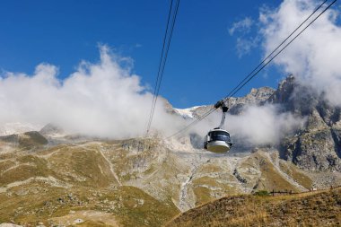 Güneşli bir yaz gününde İtalyan Alplerinin sıradağları, Kayaların yakın görüntüsü, Bulutlu Mavi Gökyüzü ve The Cableway.