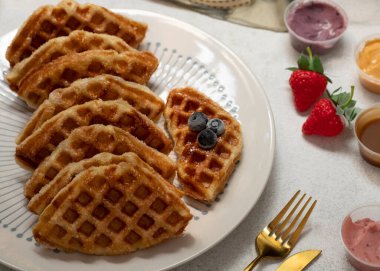 Kruvasan Waffle ya da beyaz arka planda Croffle adında devasa bir isim. Çeşitli soslarla servis edilmiş. Seçici Odaklanma