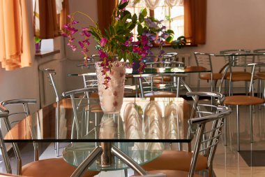 Kafenin içinde paslanmaz çelikten yapılmış boş cam masalar ve sandalyeler. 