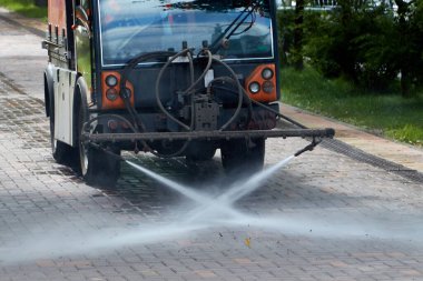 Şehirde kaldırımı yıkayan bir araba.