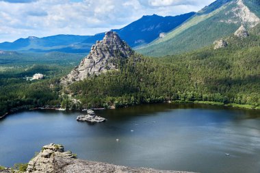 Kazakistan 'daki Burabay Ulusal Parkı' nda ormanla kaplı göl ve dağların manzarası.