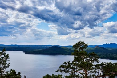 Burabay Ulusal Parkı, Kazakistan 'da dramatik bulutların, göl ve dağların panoramik manzarası ormanla kaplıdır.