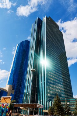 Bulutlu mavi gökyüzünün arka planına cam cepheli yüksek binalar.