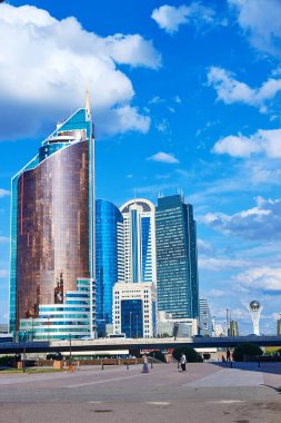 Bulutlu mavi gökyüzünün arka planına cam cepheli yüksek binalar.