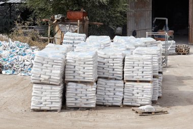 Deponun bahçesindeki paletlerin üzerinde alçıtaşı torbaları var.