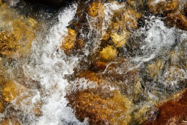 Suyun kaynayan dokusu akıntıdaki bir dağ nehrinin kayaları arasında. Yumuşak odaklı bulanık hareketin soyut arkaplanı