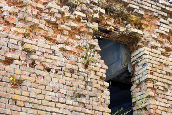 старое заброшенное здание из красного кирпича без оконных рам и рушащихся кирпичей