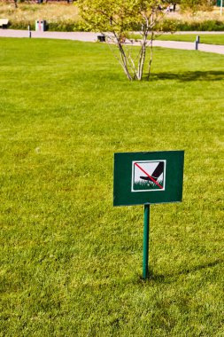 sign not to walk on the lawn installed on a green lawn in a city park