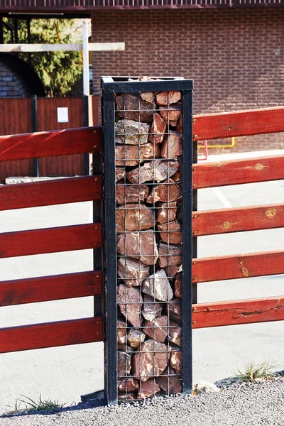 fence post made of steel corners and wire and filled with stones. decorative natural stone gabion fence