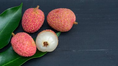 Siyah ahşap bir masada kırmızı liçi..