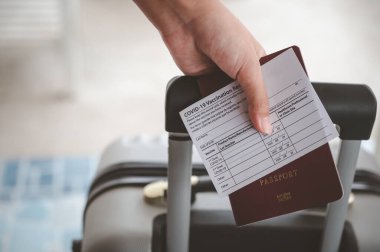Pasaportları ve koronavirüs aşısı kartını elinde tutan insanlar, yolculuk için bavulla seyahat haritası. Dünya çapında Covid-19