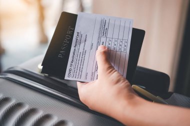 Pasaportları ve koronavirüs aşısı kartını elinde tutan insanlar, yolculuk için bavulla seyahat haritası. Dünya çapında Covid-19