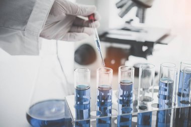 Yakın çekim pipeti laboratuardaki deney araştırmasında bir numuneyi test tüpüne atıyor.