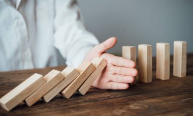 close-up hand The hand of a businessman who is stopping or preventing a falling block.Risk protection concept,Eliminating the risk.	