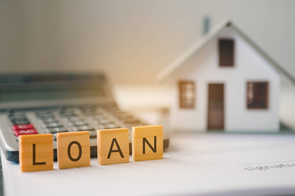 Образцовый дом с буквами "LOAN", вырезанными на деревянных блоках. Концепция договора займа на недвижимое имущество, а также займа на недвижимость.