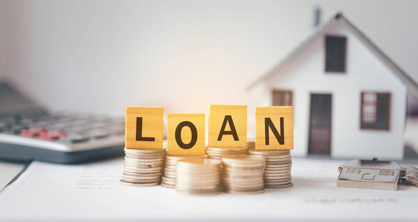 Образцовый дом с буквами "LOAN", вырезанными на деревянных блоках. Концепция договора займа на недвижимое имущество, а также займа на недвижимость.