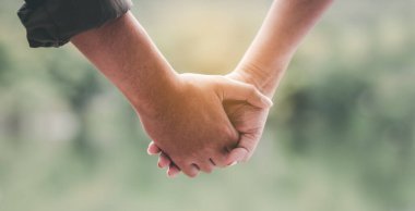 close-up of a young couple holding hands in nature