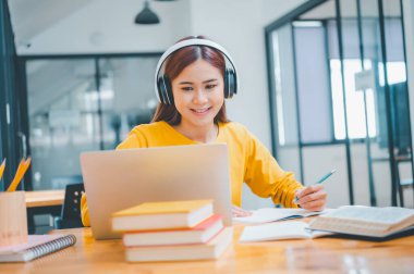  young student wearing headphones studies online, distance learning, and keeps up to date on the global coronavirus pandemic.