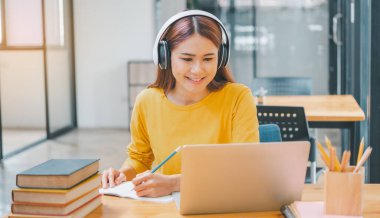 young student wearing headphones studies online, distance learning, and keeps up to date on the global coronavirus pandemic.