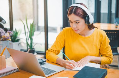  young student wearing headphones studies online, distance learning, and keeps up to date on the global coronavirus pandemic.
