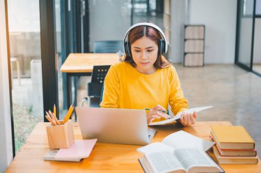  young student wearing headphones studies online, distance learning, and keeps up to date on the global coronavirus pandemic.