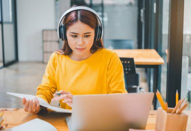  young student wearing headphones studies online, distance learning, and keeps up to date on the global coronavirus pandemic.