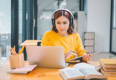  young student wearing headphones studies online, distance learning, and keeps up to date on the global coronavirus pandemic.