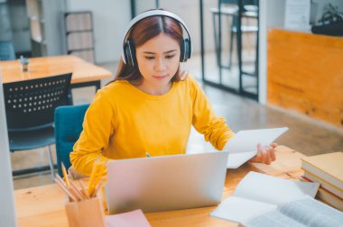  young student wearing headphones studies online, distance learning, and keeps up to date on the global coronavirus pandemic.