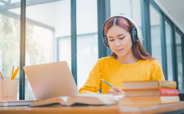  young student wearing headphones studies online, distance learning, and keeps up to date on the global coronavirus pandemic.