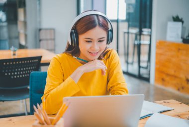  young student wearing headphones studies online, distance learning, and keeps up to date on the global coronavirus pandemic.
