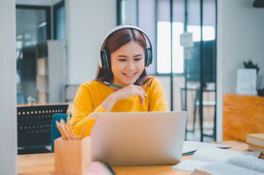  young student wearing headphones studies online, distance learning, and keeps up to date on the global coronavirus pandemic.