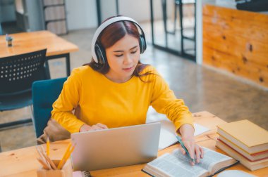  young student wearing headphones studies online, distance learning, and keeps up to date on the global coronavirus pandemic.